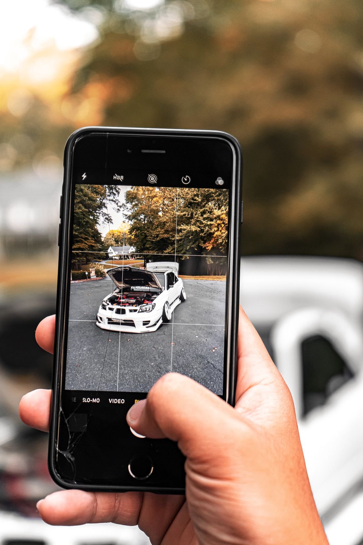 A person photographing their car with a smartphone to start a repair estimate