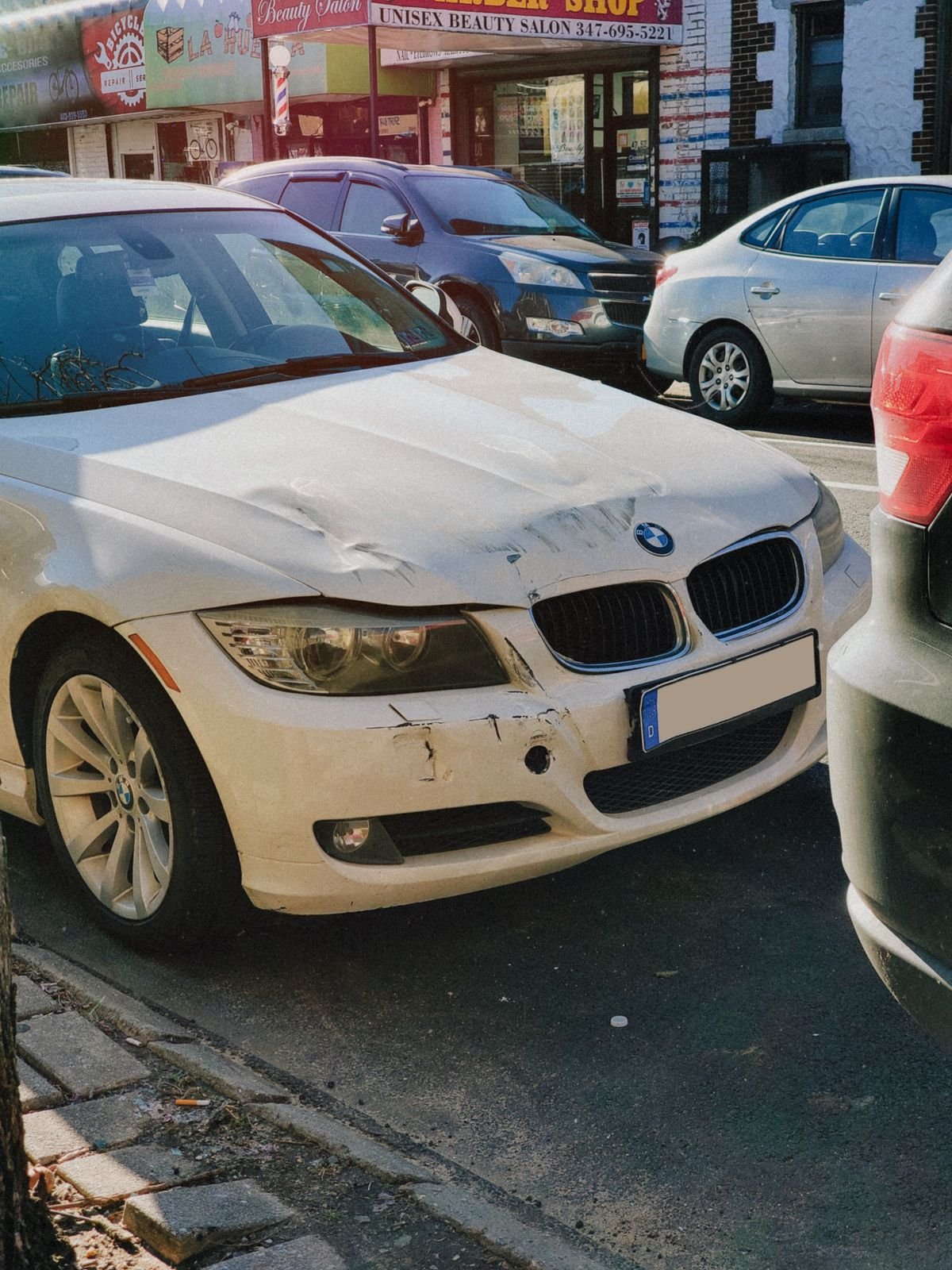 A car with front-end collision damage parked on a street