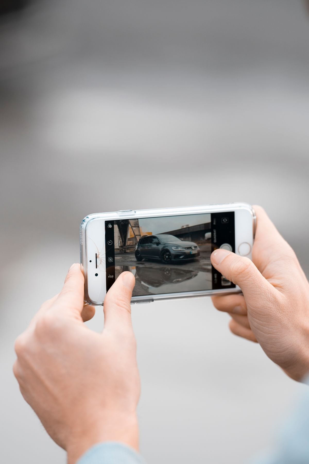 A person photographing vehicle damage with a smartphone