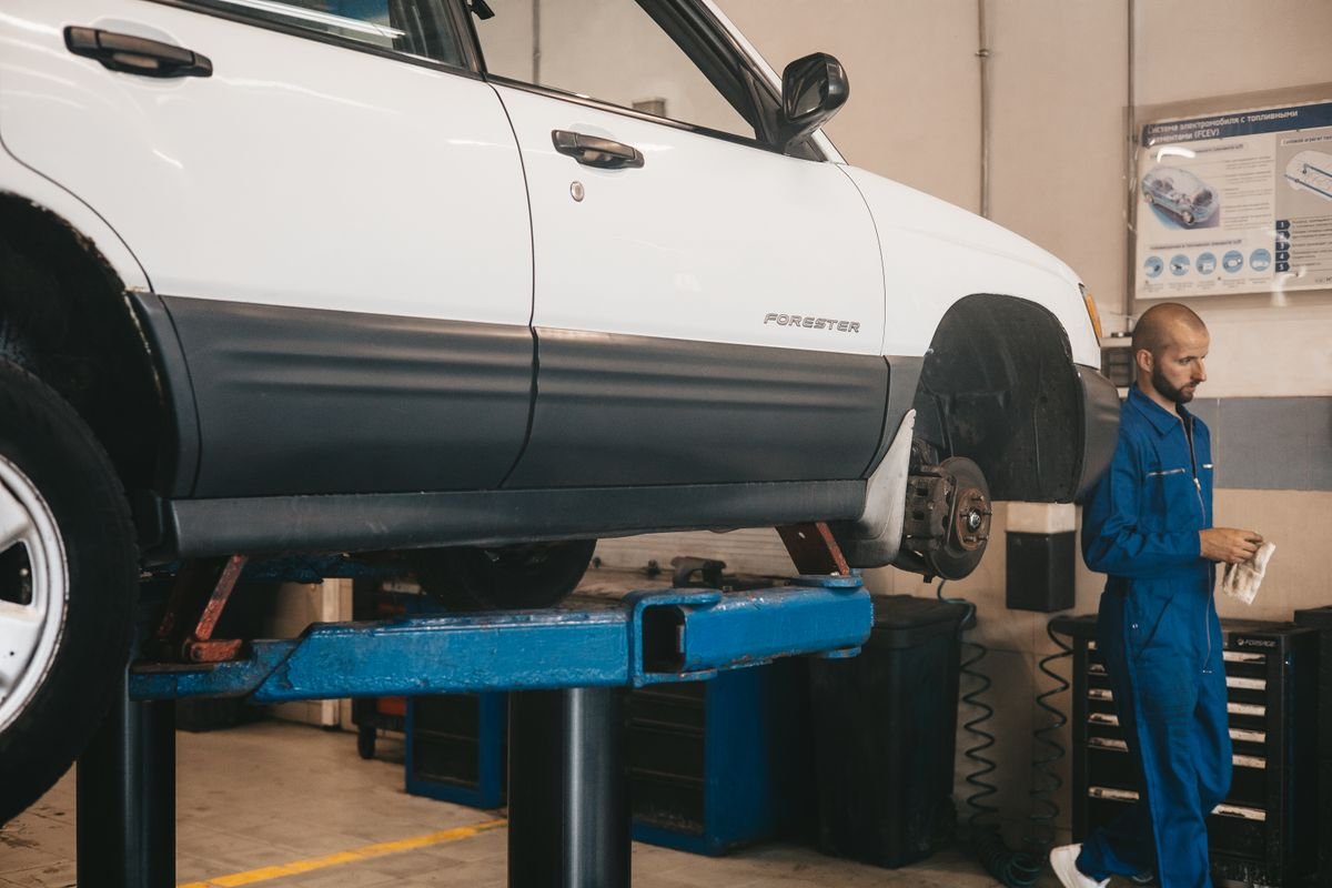 A technician inspecting a vehicle on a lift in a repair workshop