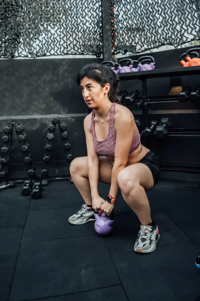 An athlete performing a kettlebell squat in a modern gym